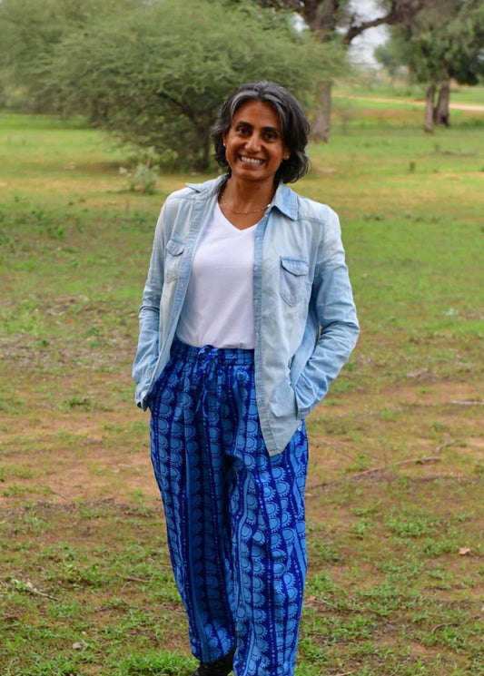 Person wearing a light blue denim jacket and blue patterned pants standing in a grassy field.