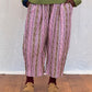 Person wearing a green sweater and patterned trousers standing on a wooden floor.