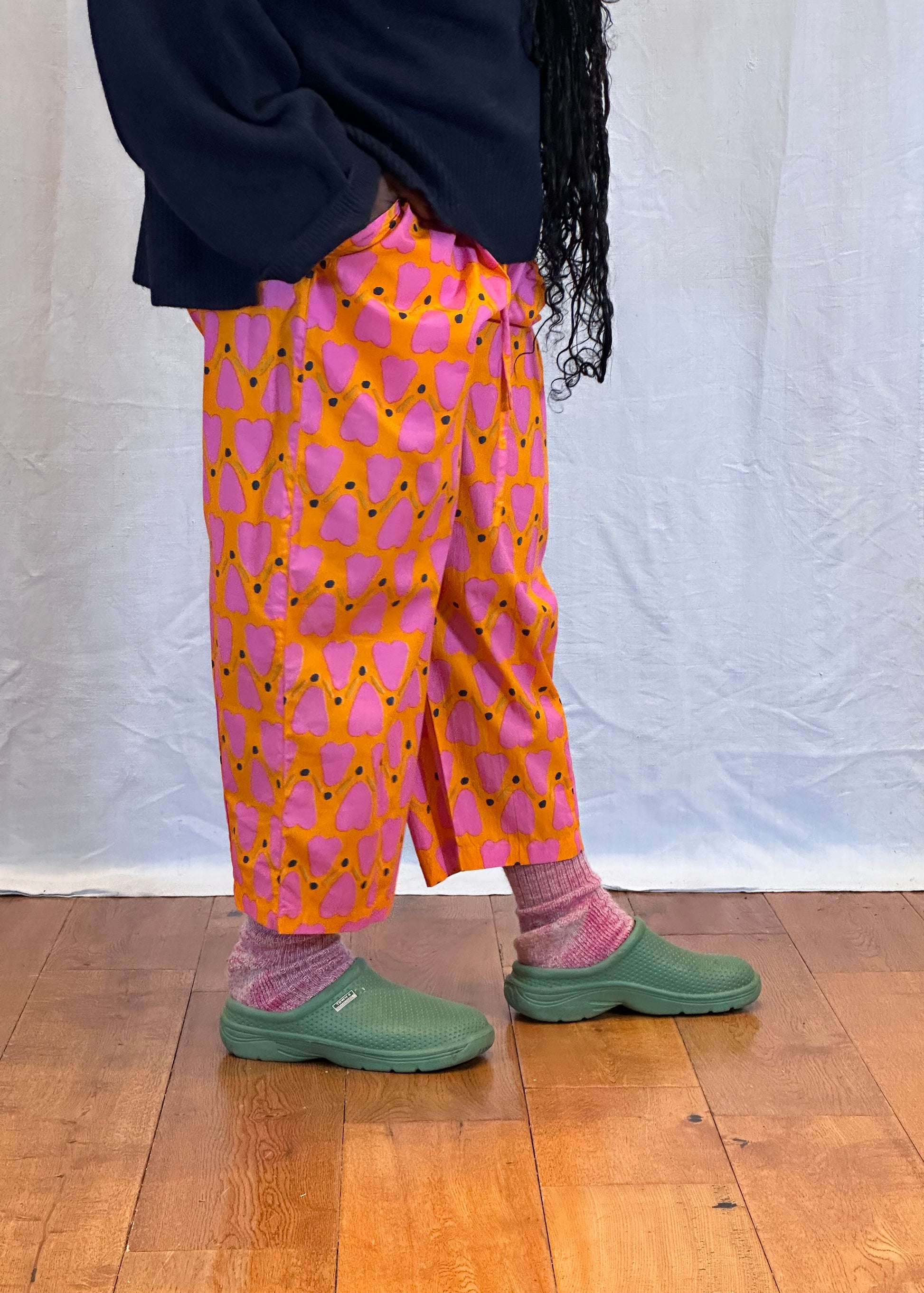 Person wearing colourful pants and green shoes on a wooden floor. Humphries and Begg