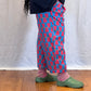 Person wearing blue pants with red heart patterns and green shoes on a wooden floor. Humphries and Begg
