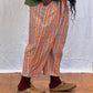 Person wearing a green sweater and orange striped pants on a wooden floor. Humphries and Begg