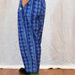 Person wearing blue patterned trousers on a wooden floor.