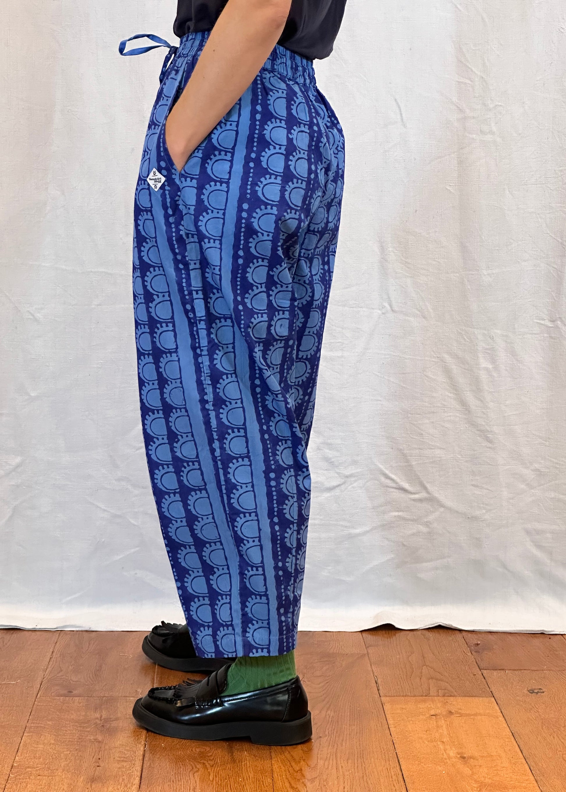 Person wearing blue patterned trousers on a wooden floor.