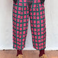 Person wearing red and green patterned pants on a white and wooden floor.