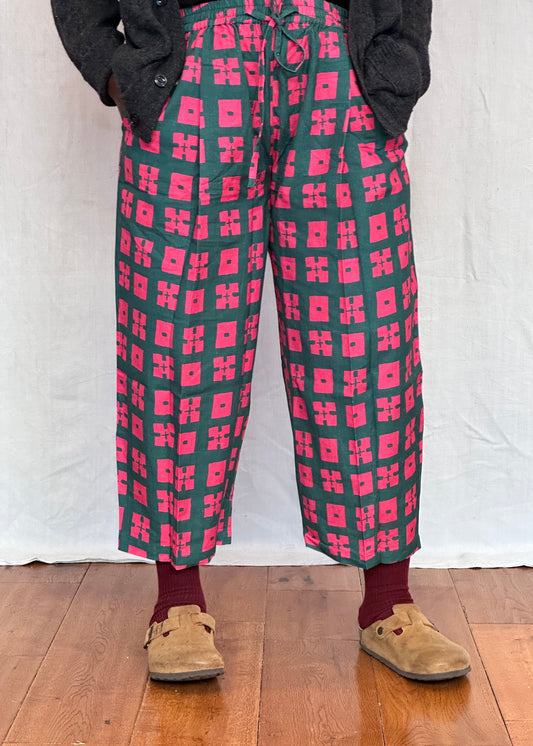 Person wearing red and green patterned pants on a white and wooden floor.