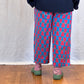 Person wearing a navy sweater and patterned trousers on a wooden floor.