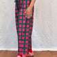 Person wearing red and black patterned leggings on a white and wooden floor.
