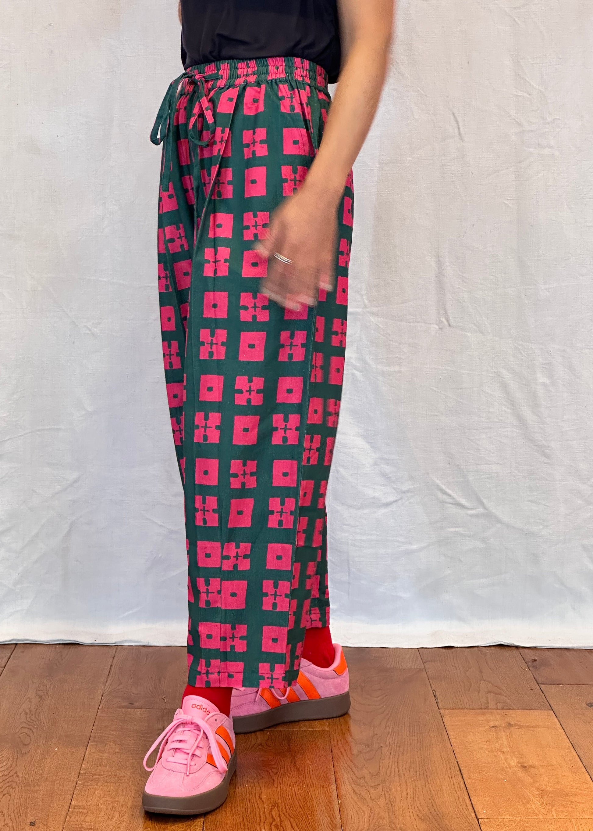 Person wearing red and black patterned leggings on a white and wooden floor.