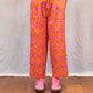 Person wearing pink and orange patterned pants on a wooden floor. Humphries and Begg