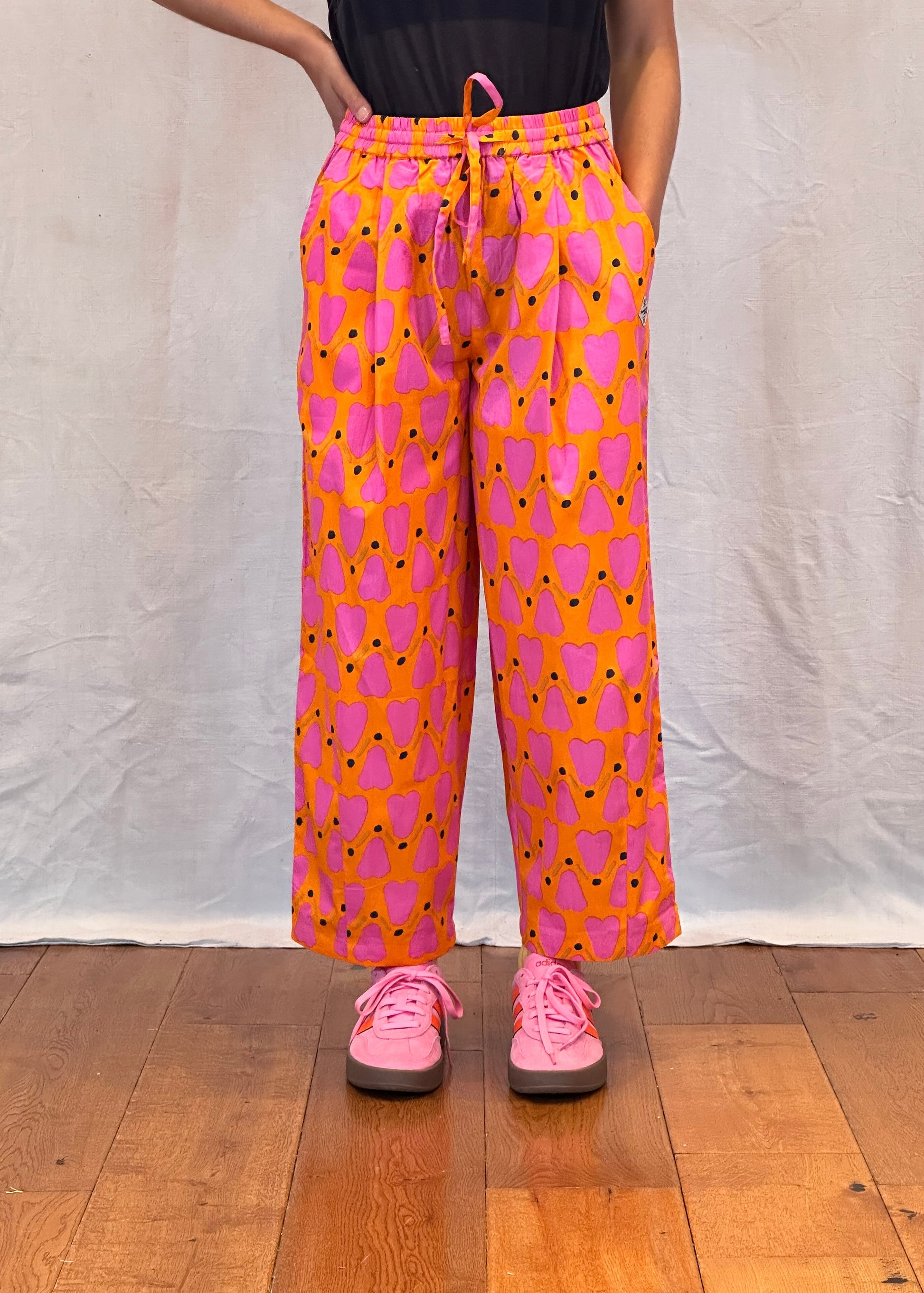 Person wearing pink and orange patterned pants on a wooden floor. Humphries and Begg