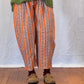 Person wearing a green sweater and striped trouser on a wooden floor. Humphries and Begg