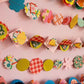 Colorful paper garland with various shapes on a pink background